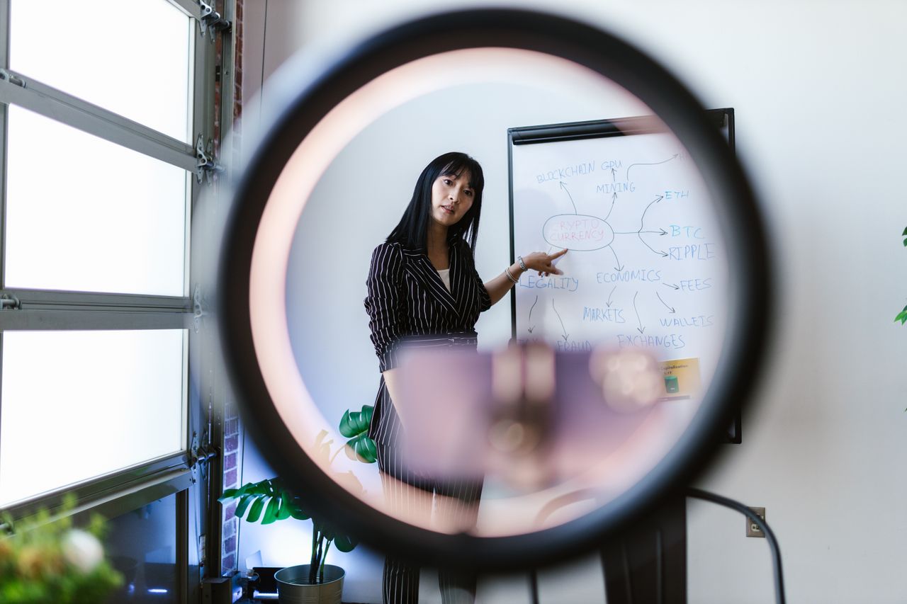 Una donna utilizza un ring light per una presentazione online su economia e criptovalute.